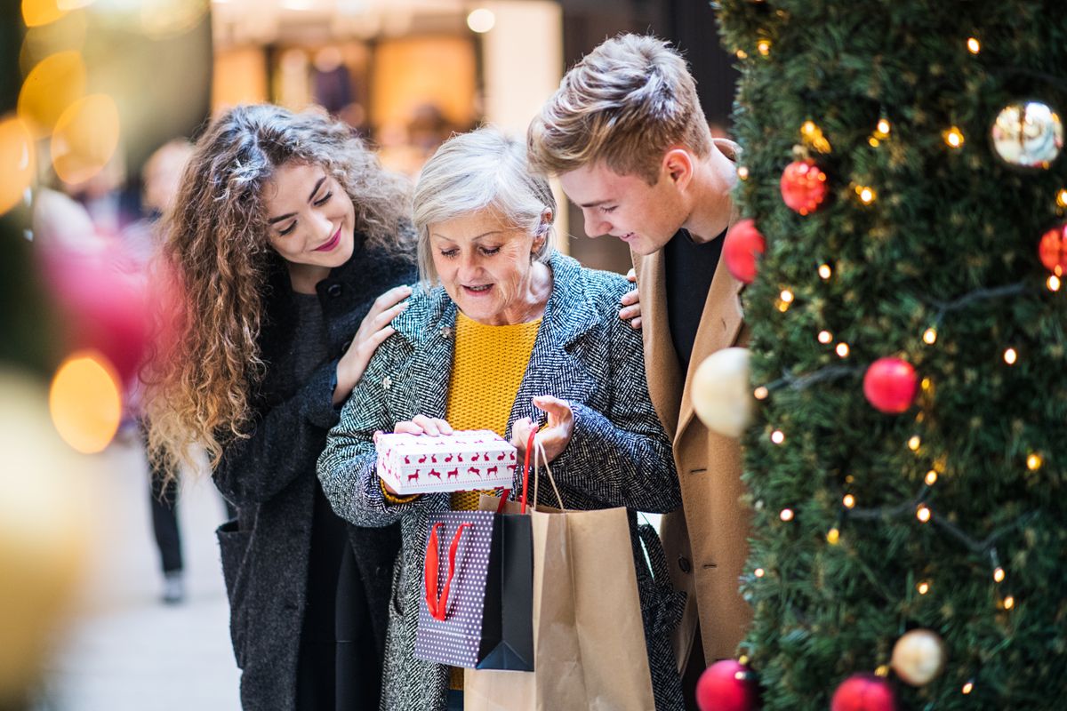 A,Young,Couple,Giving,A,Present,To,Grandmother,In,Shopping
