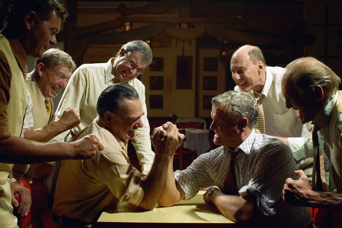 Group of men watching two men arm wrestling