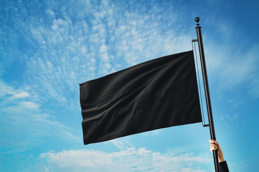 Black,Flag,Waving,On,A,Flagpole,Held,By,A,Person